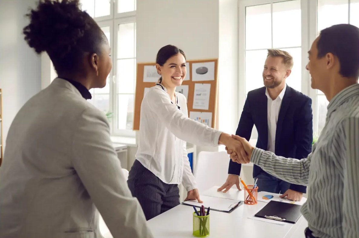 Employer welcoming a new hire with a handshake in a bright office